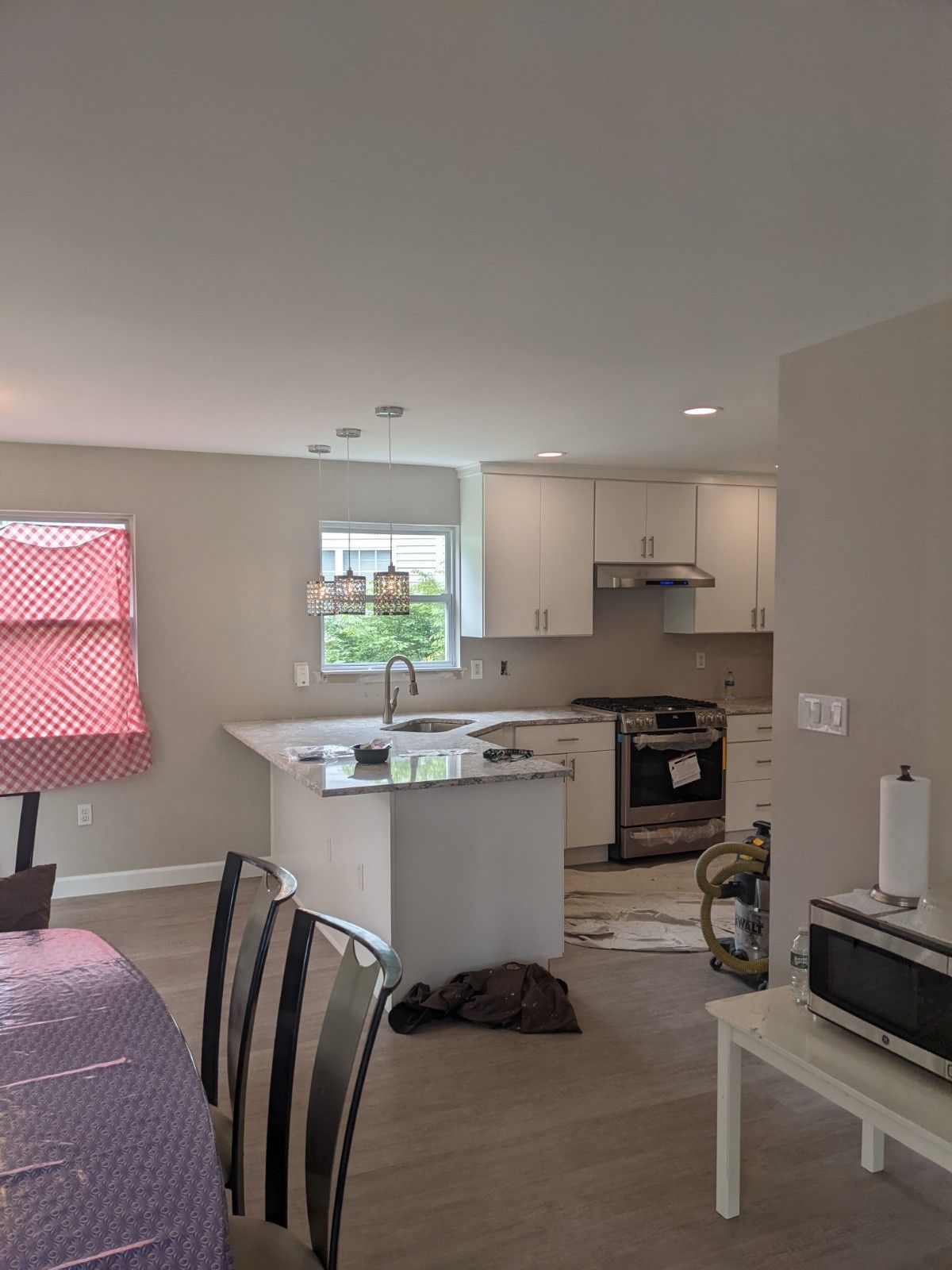 A modern kitchen featuring white cabinets, stainless steel appliances, and a central island with a view of a window.
