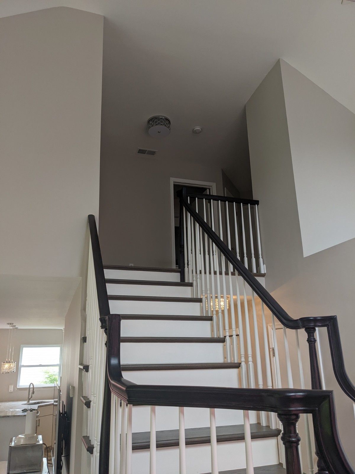 A staircase with dark wooden steps and handrails and white spindles, leading up to an open landing in a home.