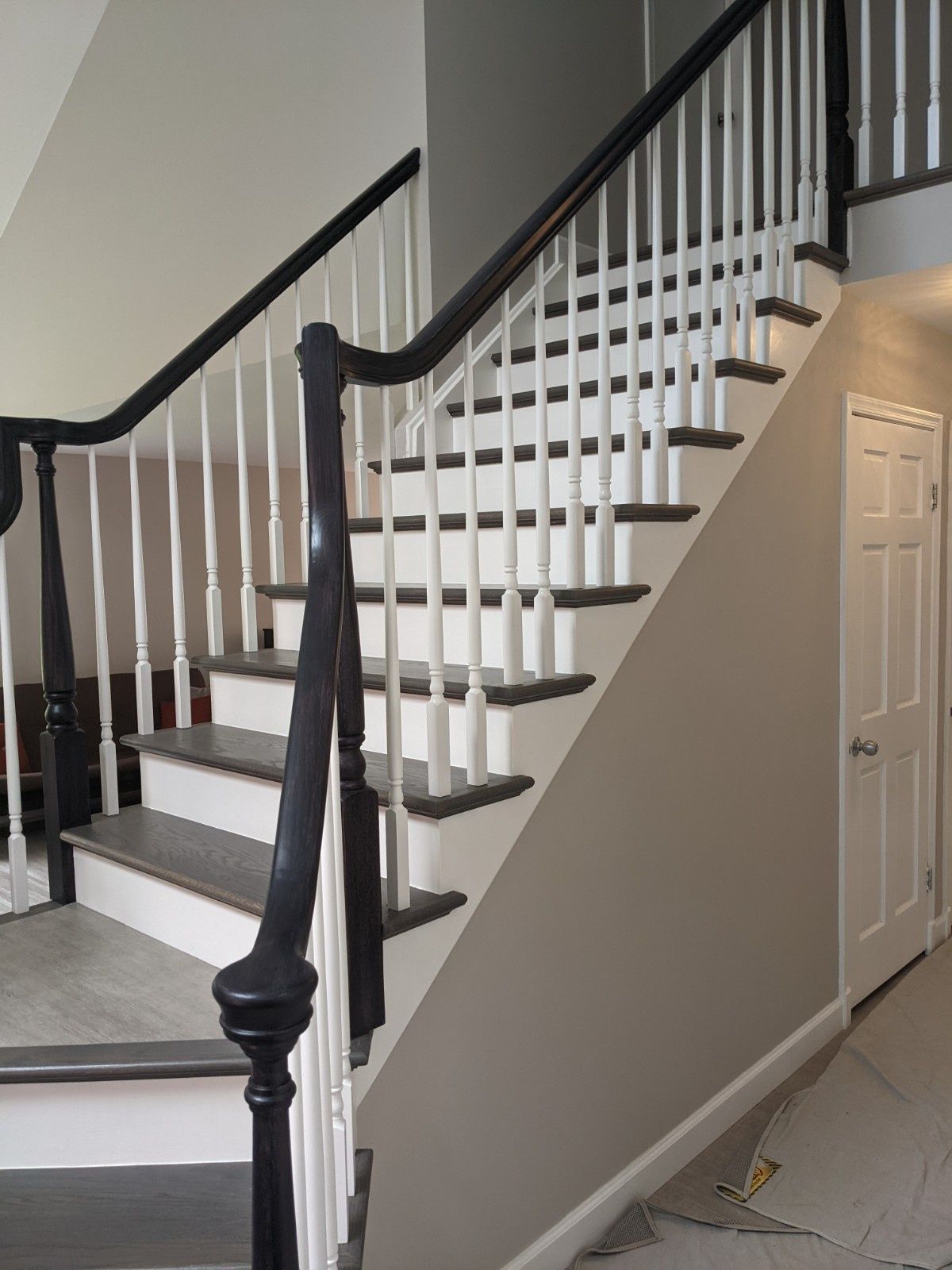 A staircase with dark-stained wooden treads and handrails, complemented by white balusters and white risers.