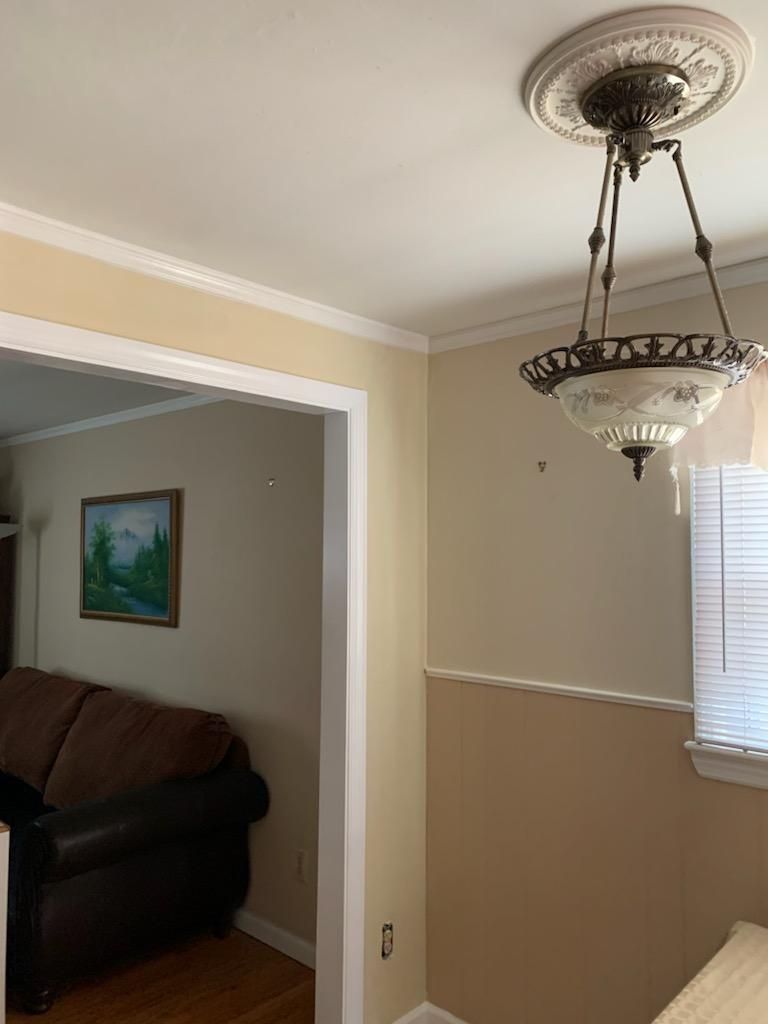 An interior room view with beige walls, a hanging dome chandelier with a medallion, and a doorway to a living room.