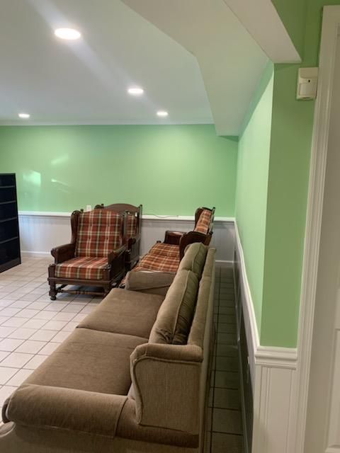 A brown sofa and plaid armchair in a room with light green walls and tile floors.