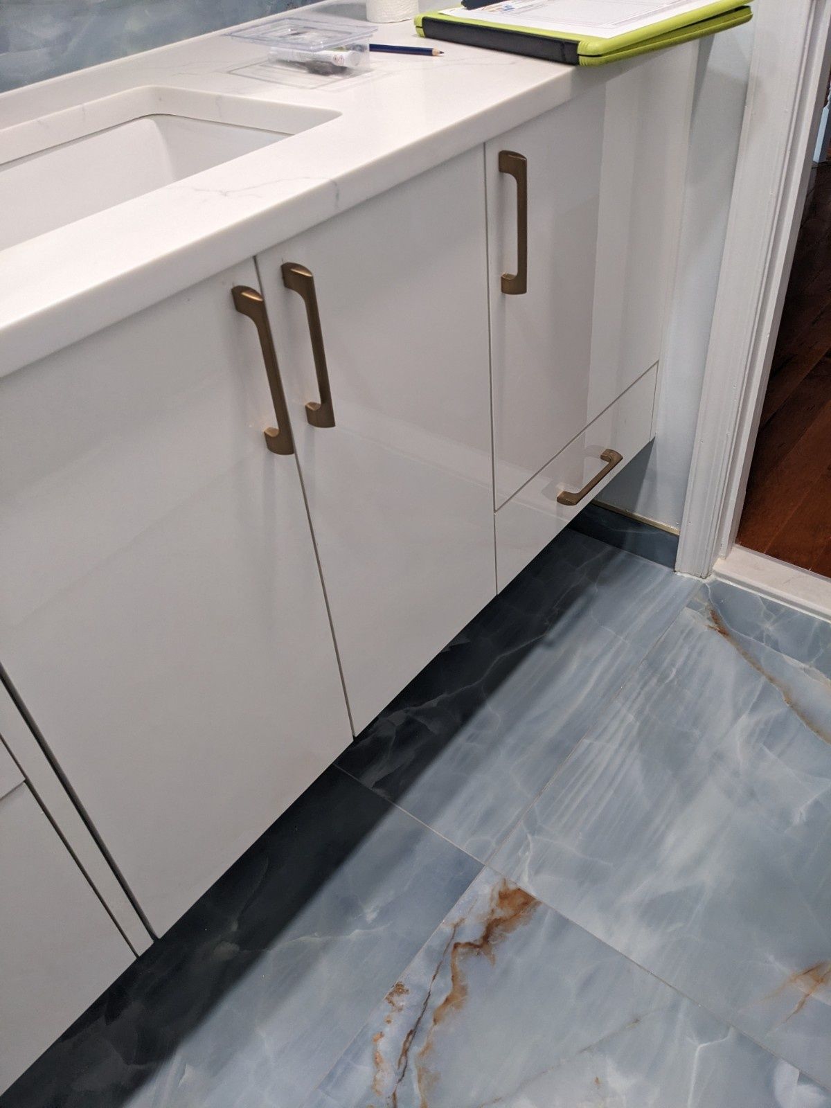 A white bathroom vanity with gold-toned hardware, set above blue and white patterned tile flooring.