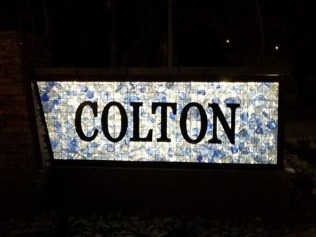 A sign that says colton is lit up at night