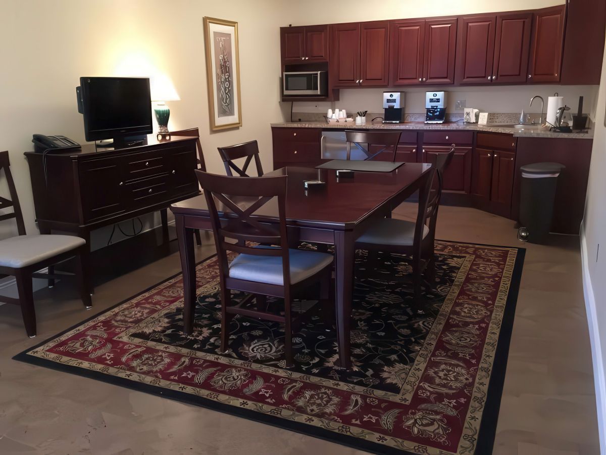 Dining area with a table, chairs, cabinets, a microwave, and a rug.