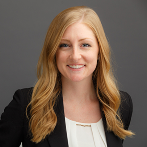 A woman wearing a black jacket and a white shirt is smiling for the camera.