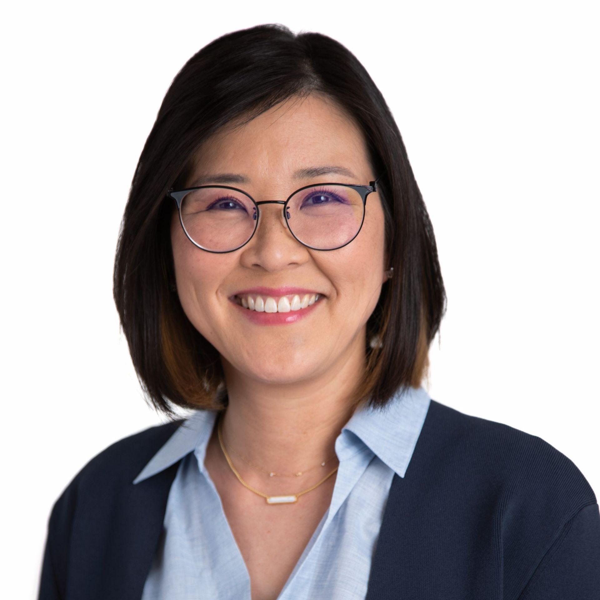A woman wearing glasses and a blue shirt is smiling