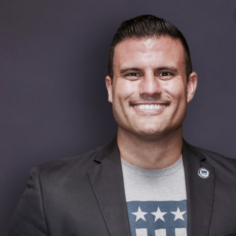 A man in a suit and a t-shirt with stars on it is smiling