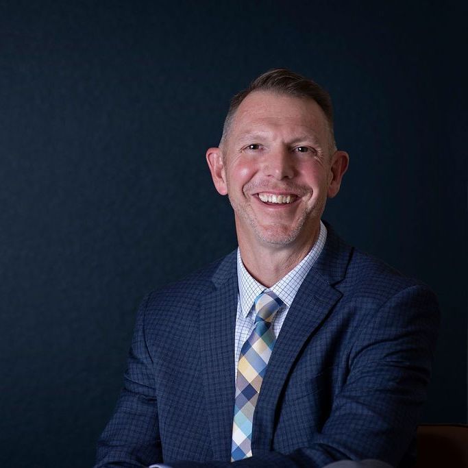 A man in a suit and tie is smiling for the camera.
