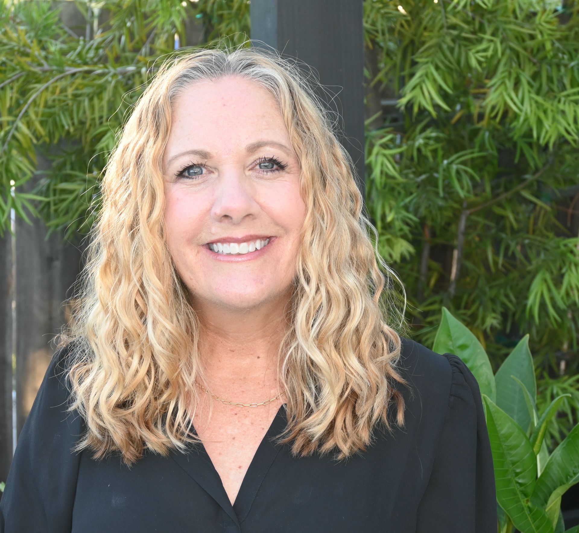 A woman with blonde hair and a black shirt is smiling for the camera.