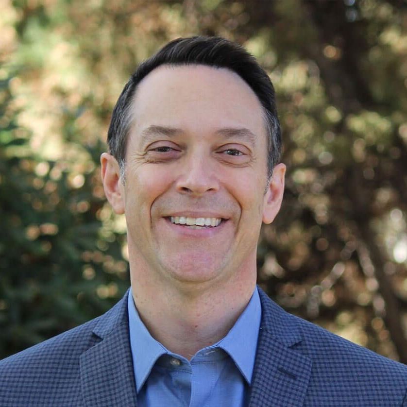 A man in a suit and blue shirt is smiling for the camera.
