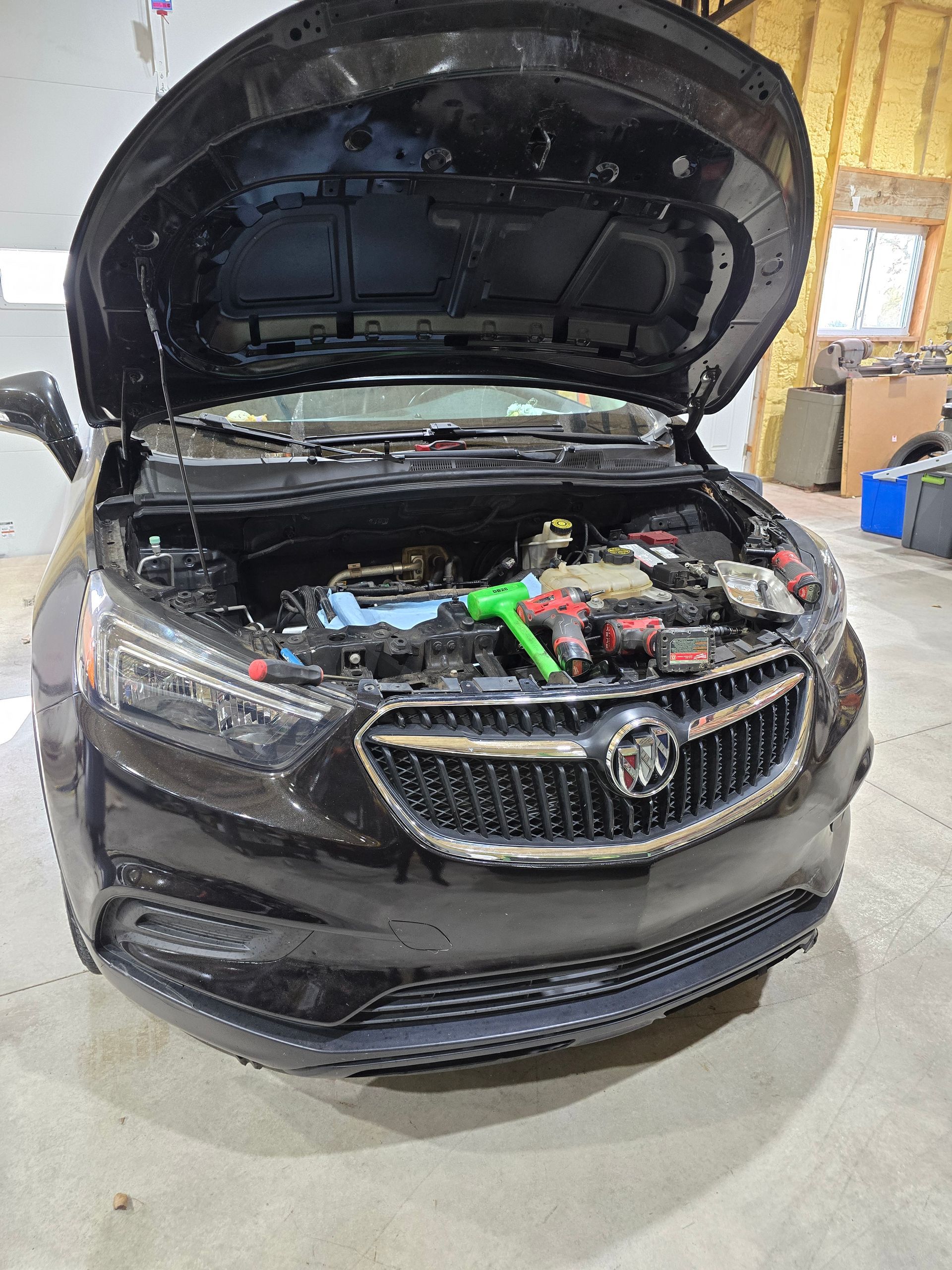 Black sedan in a garage with its hood open, showing the engine bay.