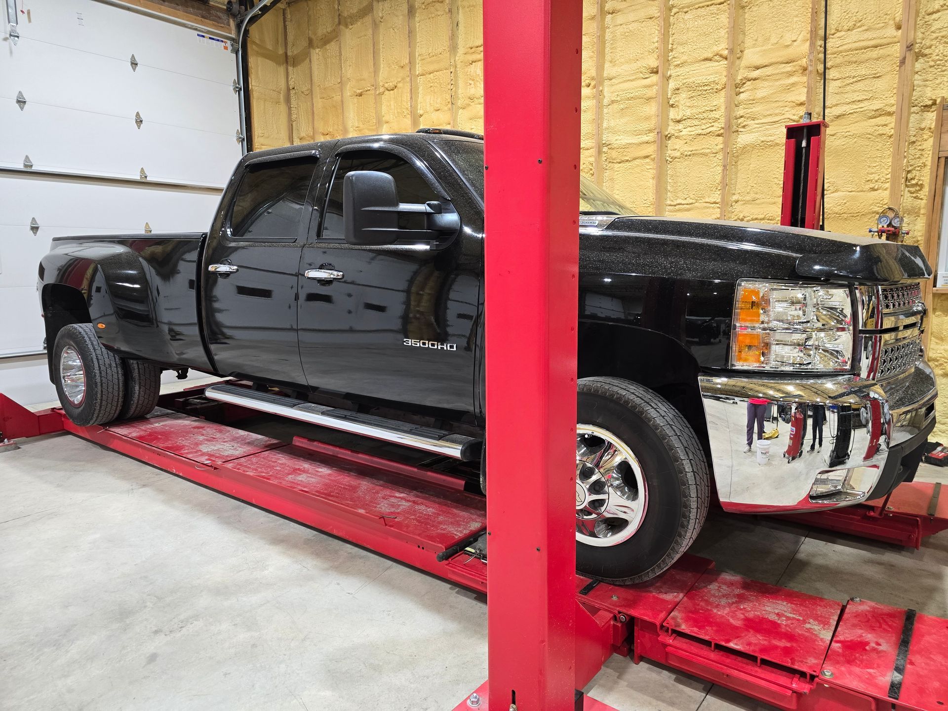 Black lifted pickup truck on a red car lift inside a garage