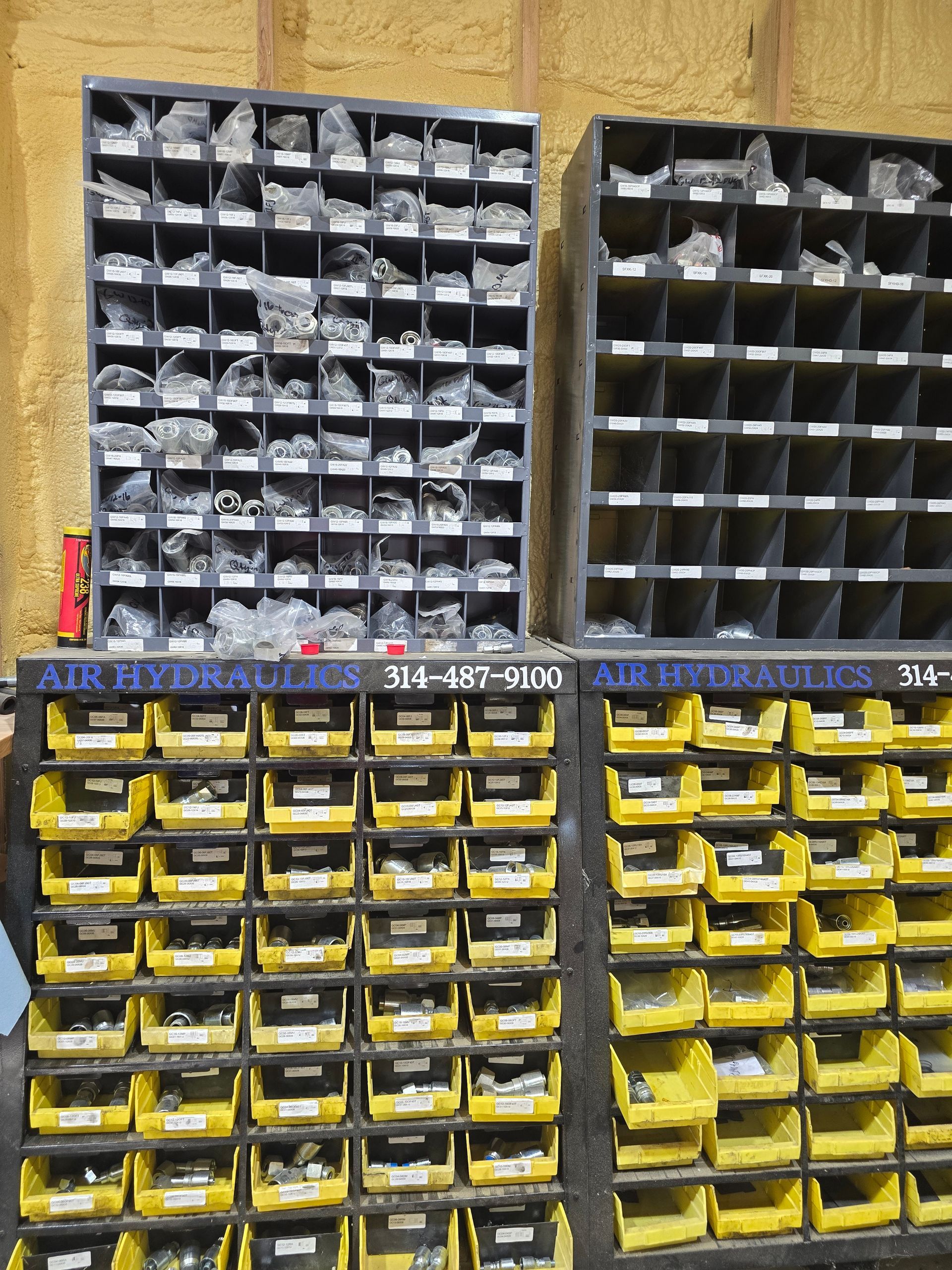 Wall of small labeled parts bins, black and yellow drawers stacked in an organized workshop storage unit