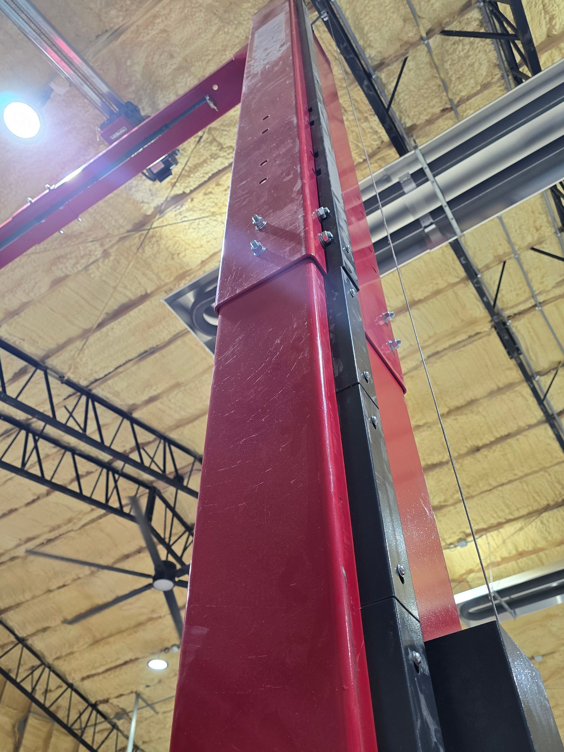 Close-up of a red steel beam and overhead truss inside an industrial building