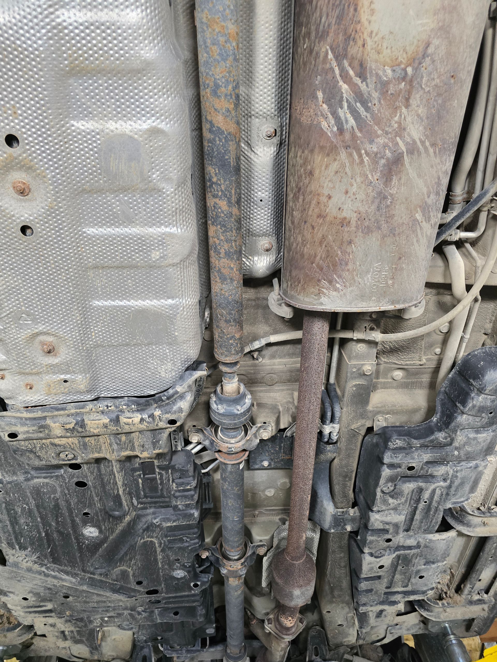 Undercarriage of a vehicle with exhaust pipes, heat shielding, and wiring visible