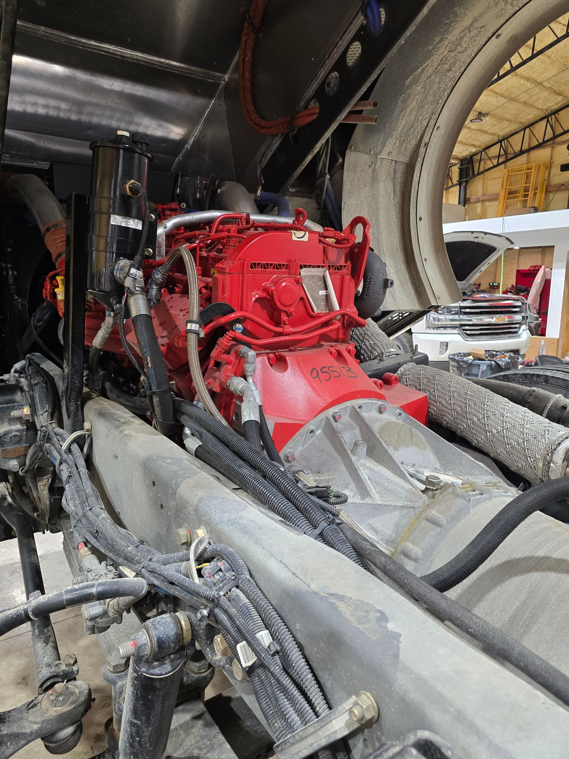 Red engine mounted inside a vehicle frame with black hoses and gray interior panels