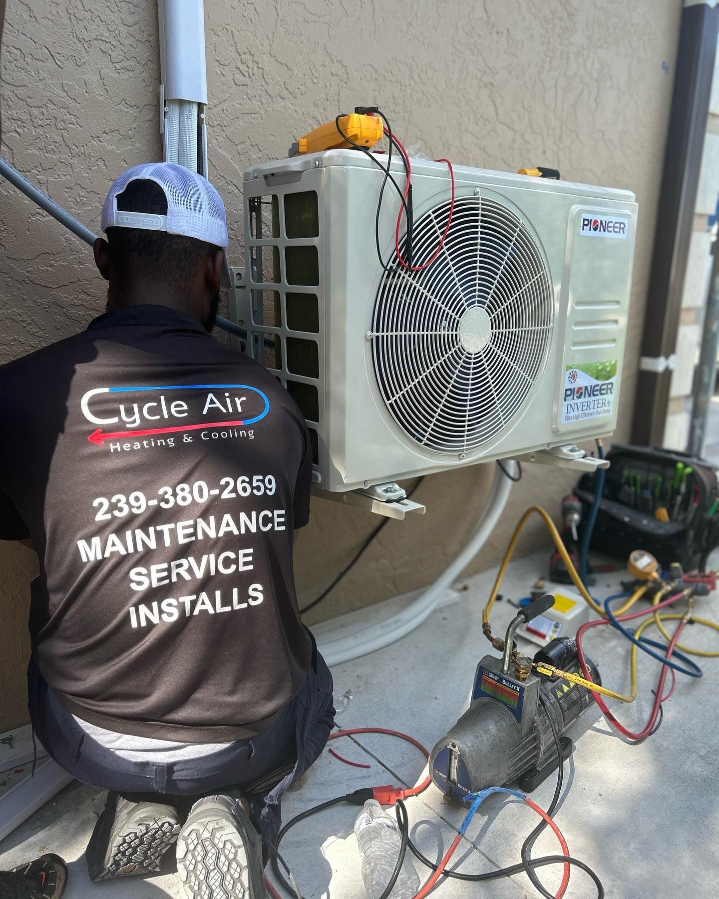 a man wearing a shirt that says curle air is working on an air conditioner
