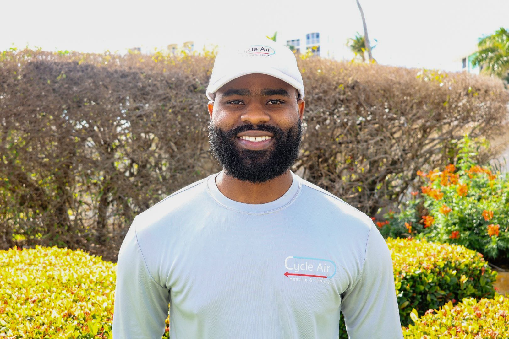 a man with a beard wearing a grey shirt and a white hat