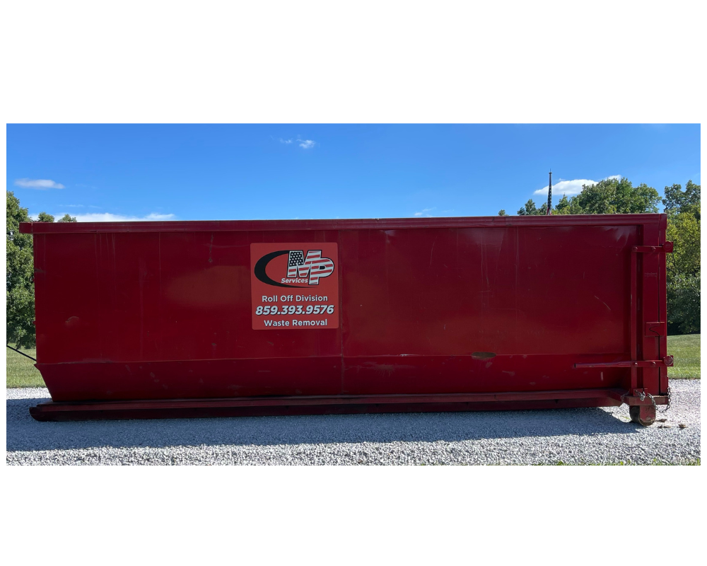 Red dumpster on gravel with blue sky in background.