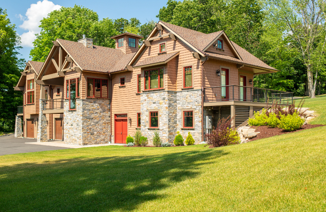 A large brick and stone house is sitting on top of a lush green hill.