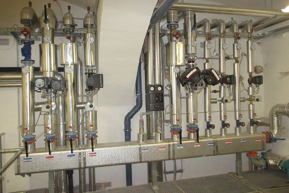 Industrielle Rohrleitungen und Ventile an einer wandmontierten mechanischen Anlage in einem Hauswirtschaftsraum