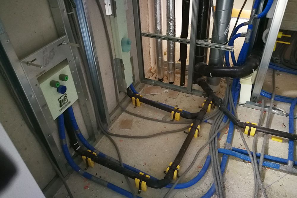 Elektrische Leitungen und Rohre in einem unfertigen Baubereich mit freiliegender Wandkonstruktion und Verteilerkästen