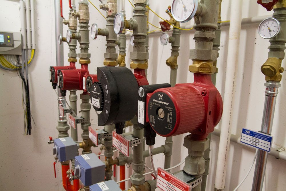 Rote und schwarze Industriepumpen und -rohre mit Manometern in einem Maschinenraum.