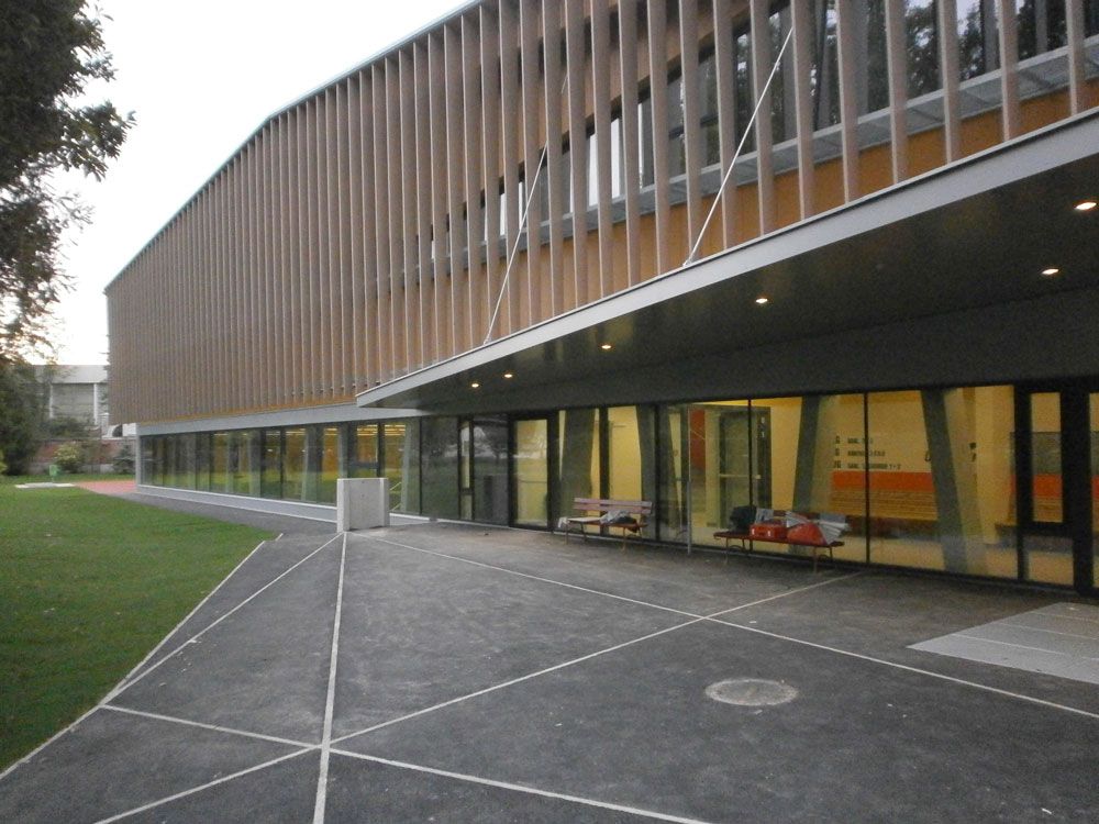 Modernes Gebäudeäußeres mit Lamellenholzfassade, Glasfenstern und gepflastertem Innenhof in der Abenddämmerung