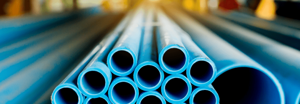 A bunch of blue pipes are stacked on top of each other in a factory.