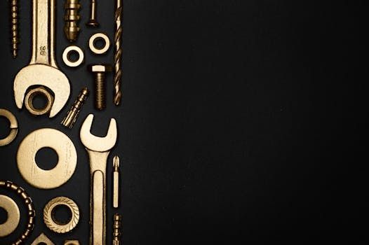Golden tools arranged against a black background. Includes wrenches, bolts, and drill bits.