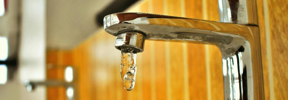 A close up of a faucet with water dripping from it.