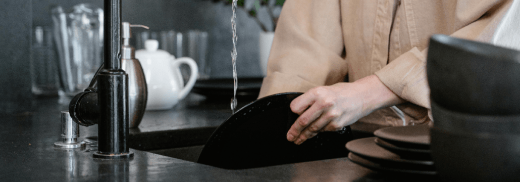 A person is washing dishes in a kitchen sink.
