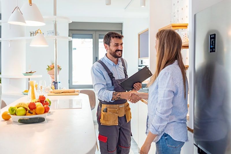 A man is shaking hands with a woman in a kitchen.