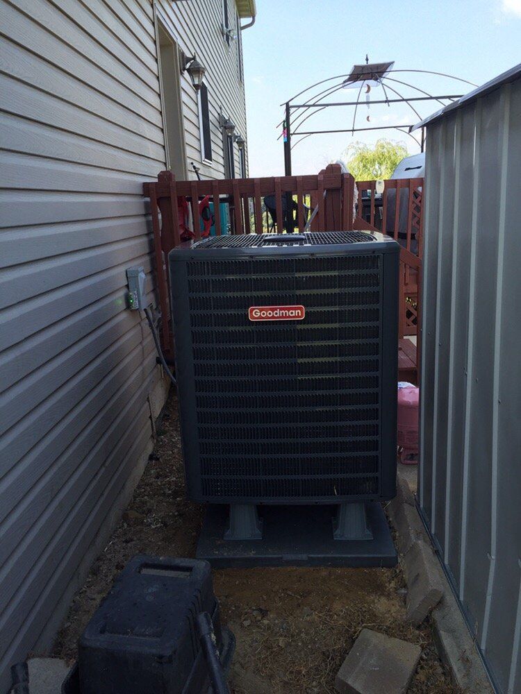 A large air conditioner is sitting on the side of a house.