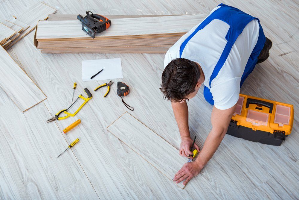 Repairman Laying Laminate Flooring — Geoff Thompson's Independent Flooring Centre In Wauchope, NSW