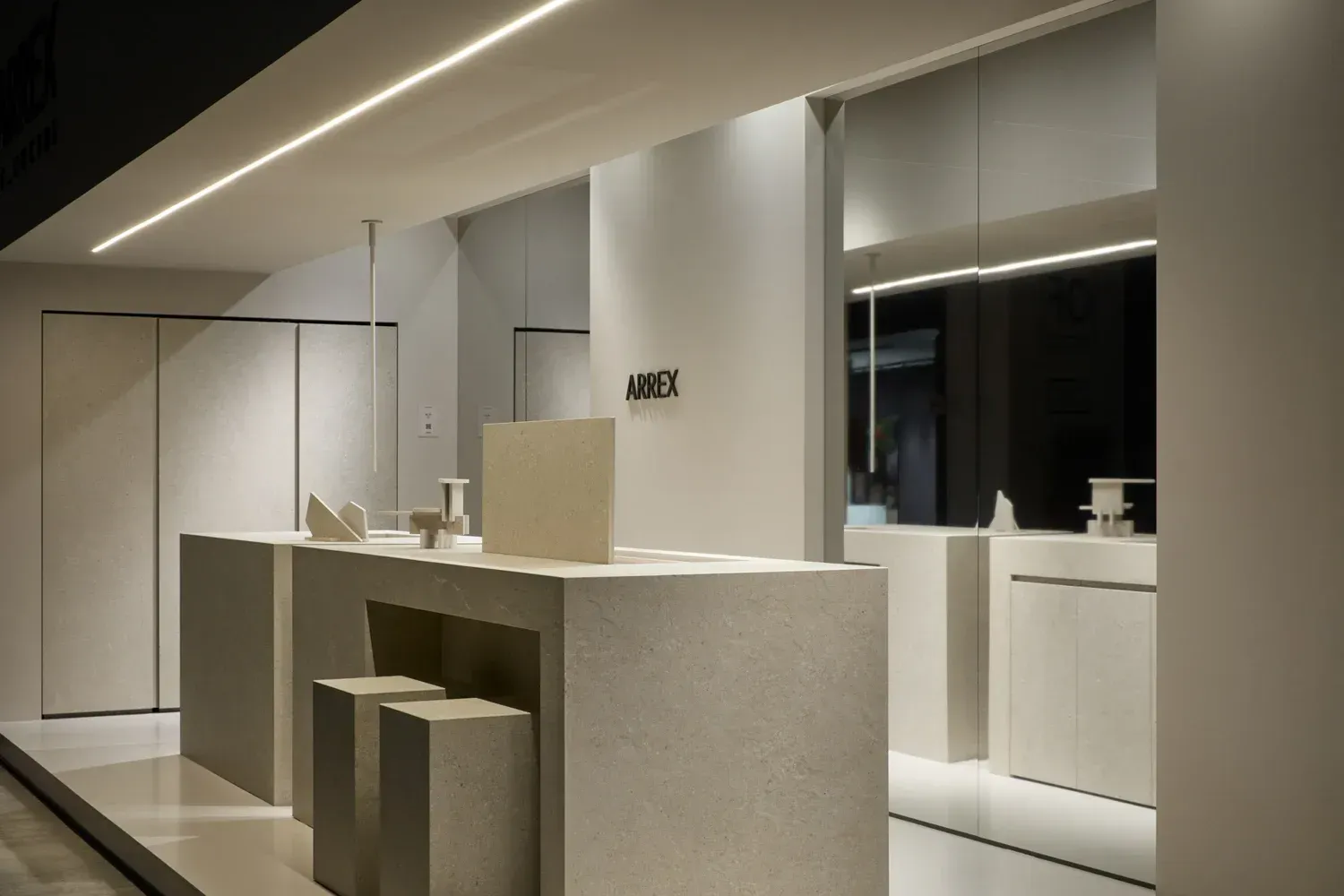 Uno spazio commerciale minimalista, completamente bianco, con luci lineari sul soffitto, un bancone, sgabelli e uno specchio.