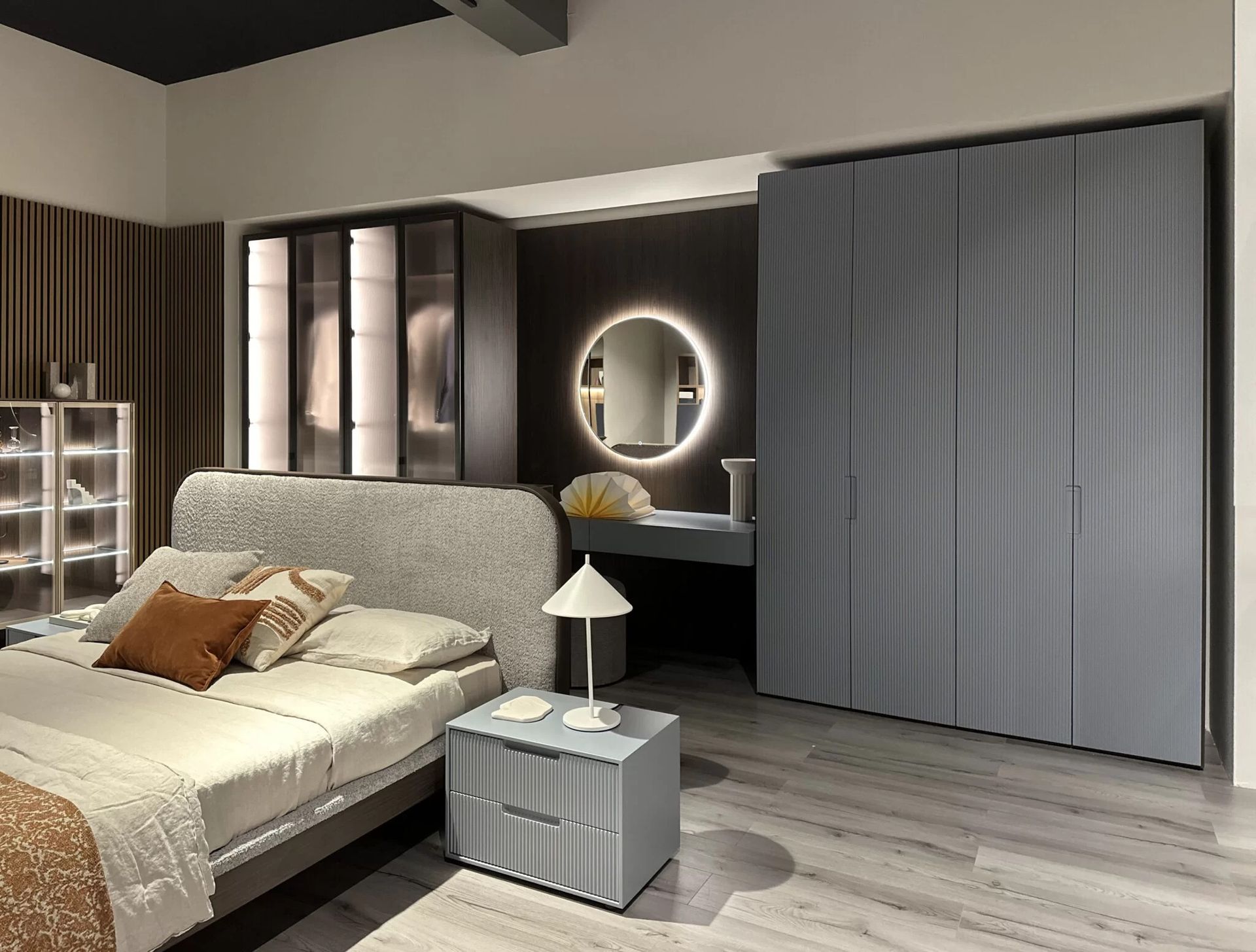 Camera da letto moderna con letto, cassettiera e armadio. I toni del grigio e del marrone dominano l'arredamento.