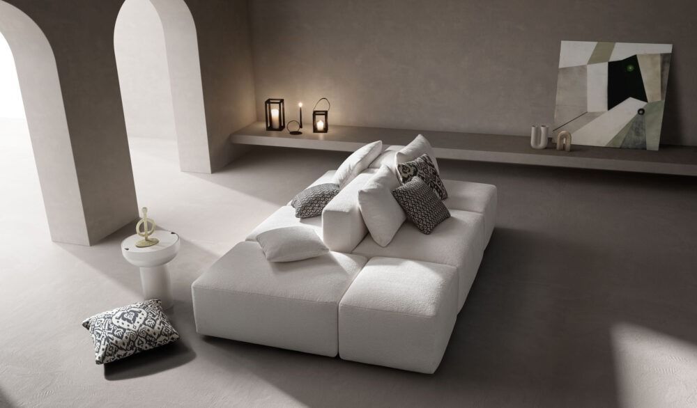 Un moderno divano modulare bianco in una stanza minimalista con toni neutri, porte ad arco ed elementi decorativi.