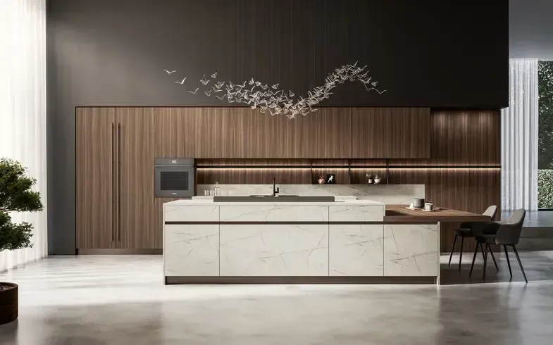 Cucina moderna con isola chiara, mobili in legno scuro e lampade decorative a sospensione. Tavolo da pranzo e sedie sulla destra.