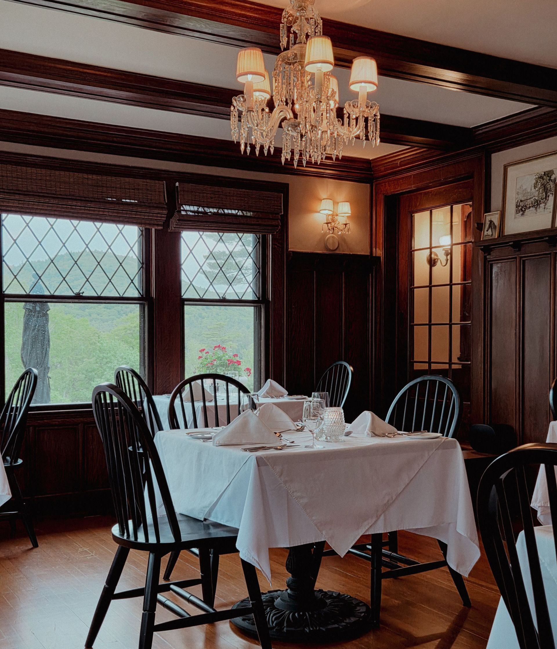 Elegant dining room with chandelier, wood paneling, and a set table by leaded windows