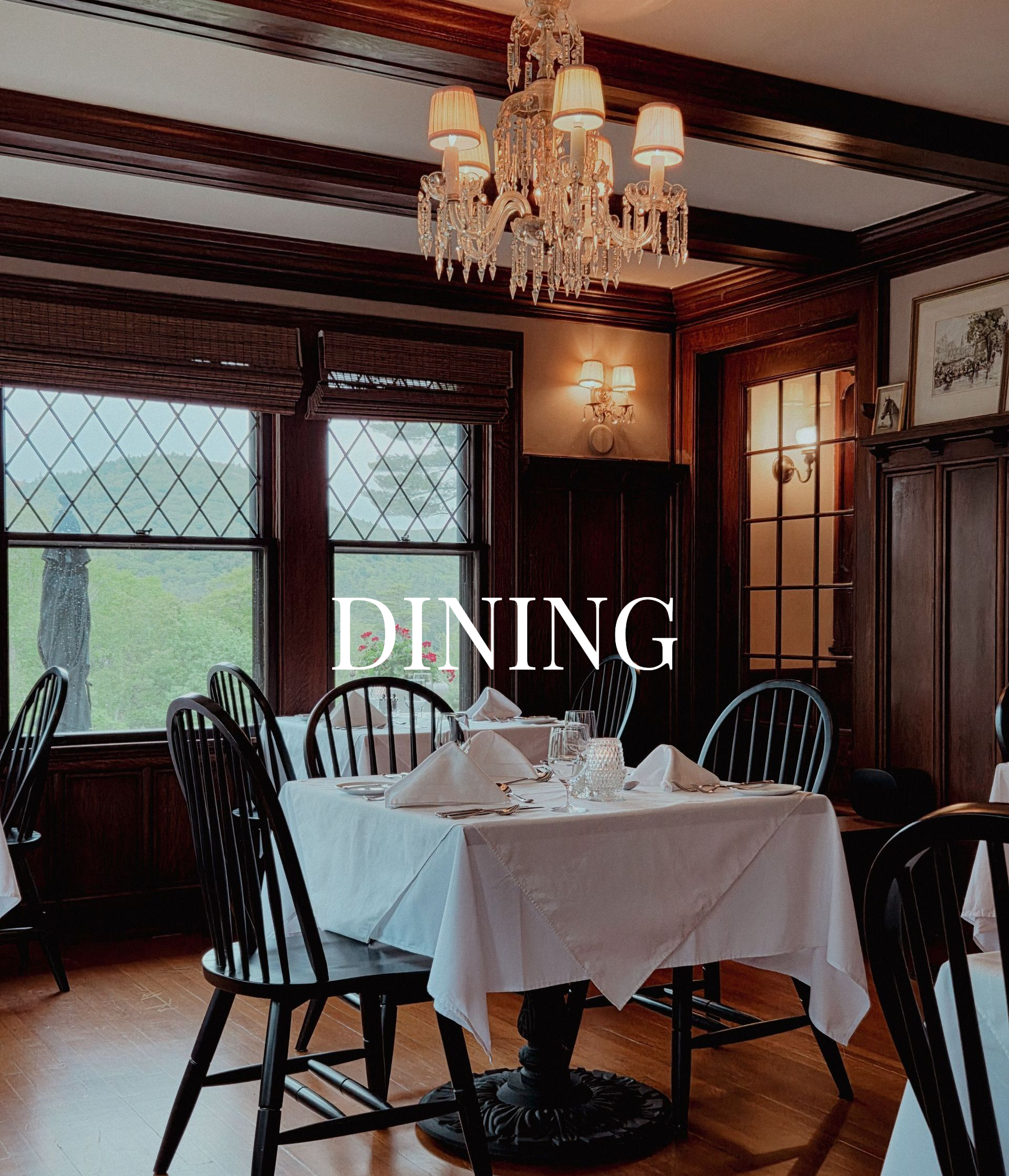 Elegant dining room with a set table, dark wood paneling, chandeliers, and large windows