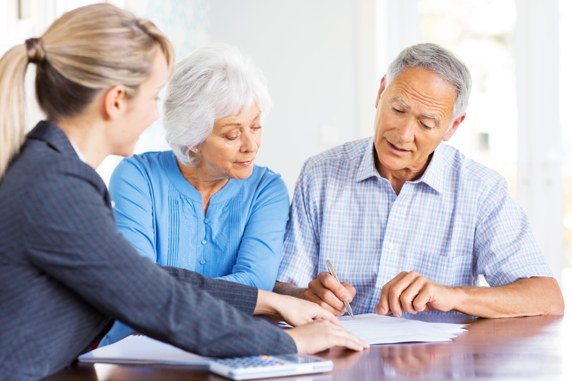 A financial advisor assisting an older couple with paperwork at a table.
