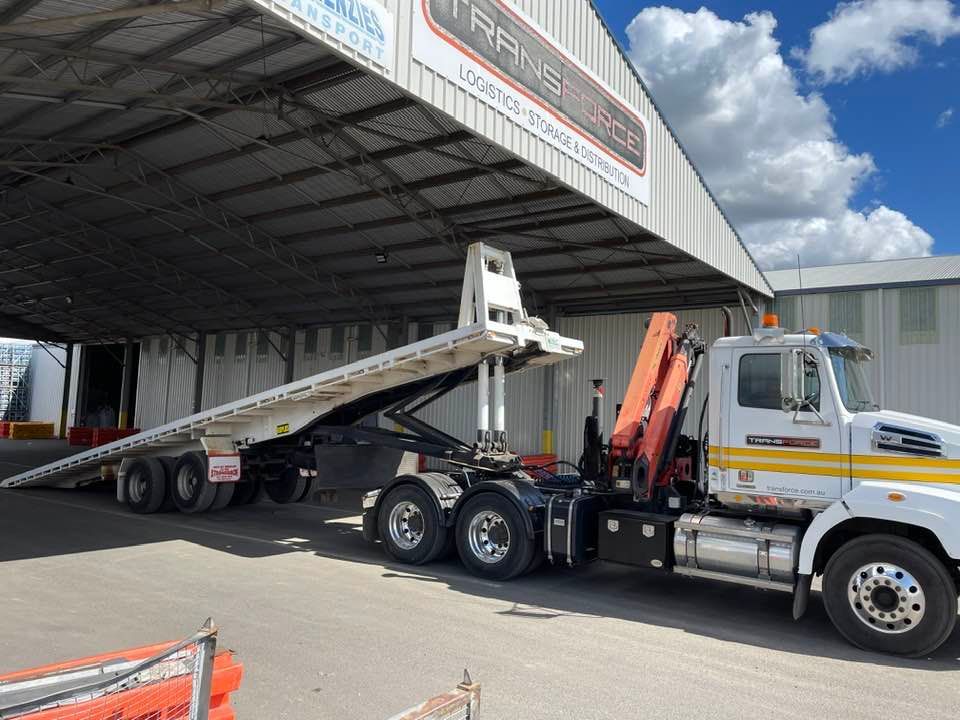 Tow Truck With a Flatbed Trailer is Parked in Front of a Building — Transforce in Sydney, NSW