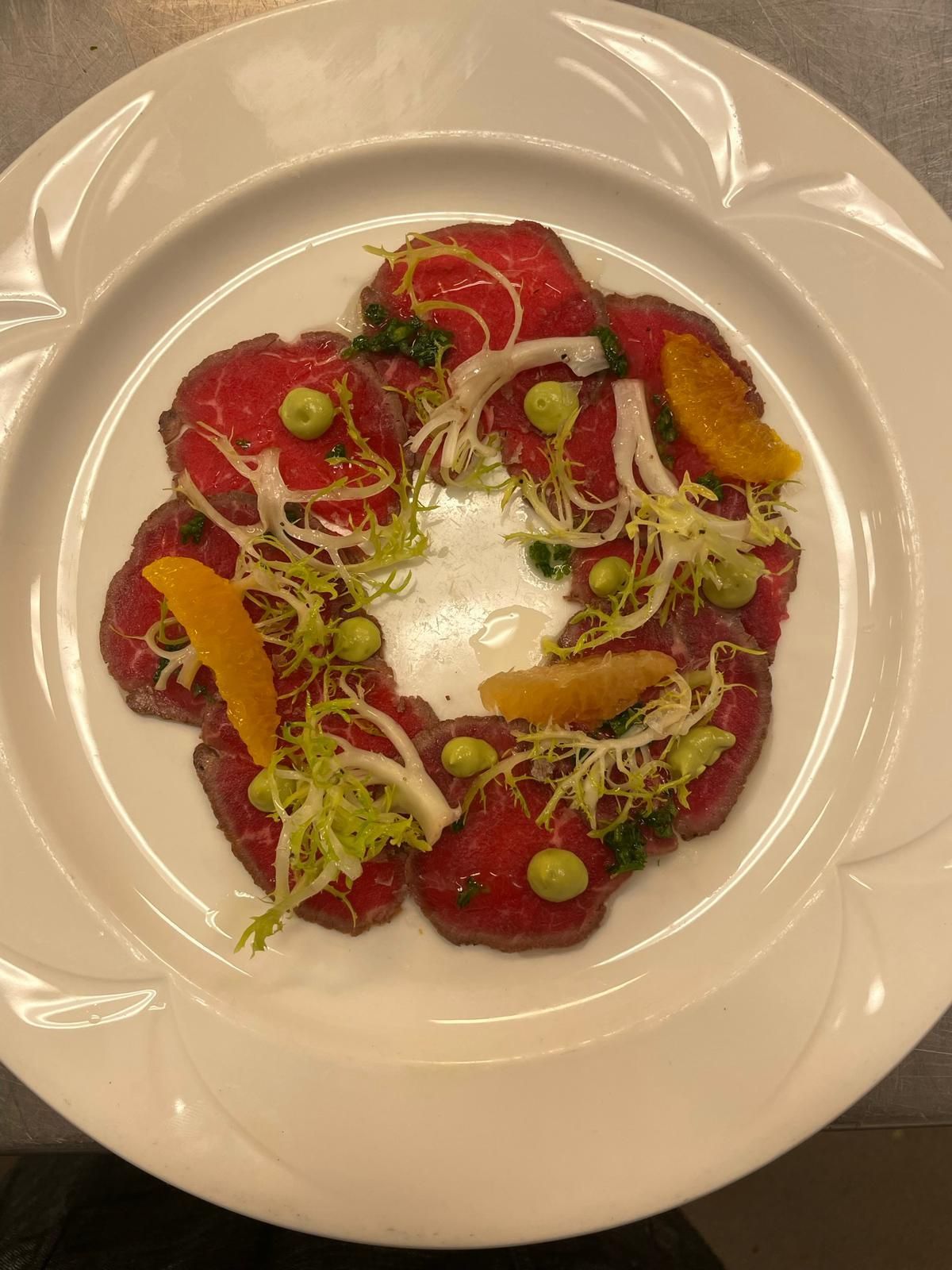A white plate topped with meat and vegetables on a table.