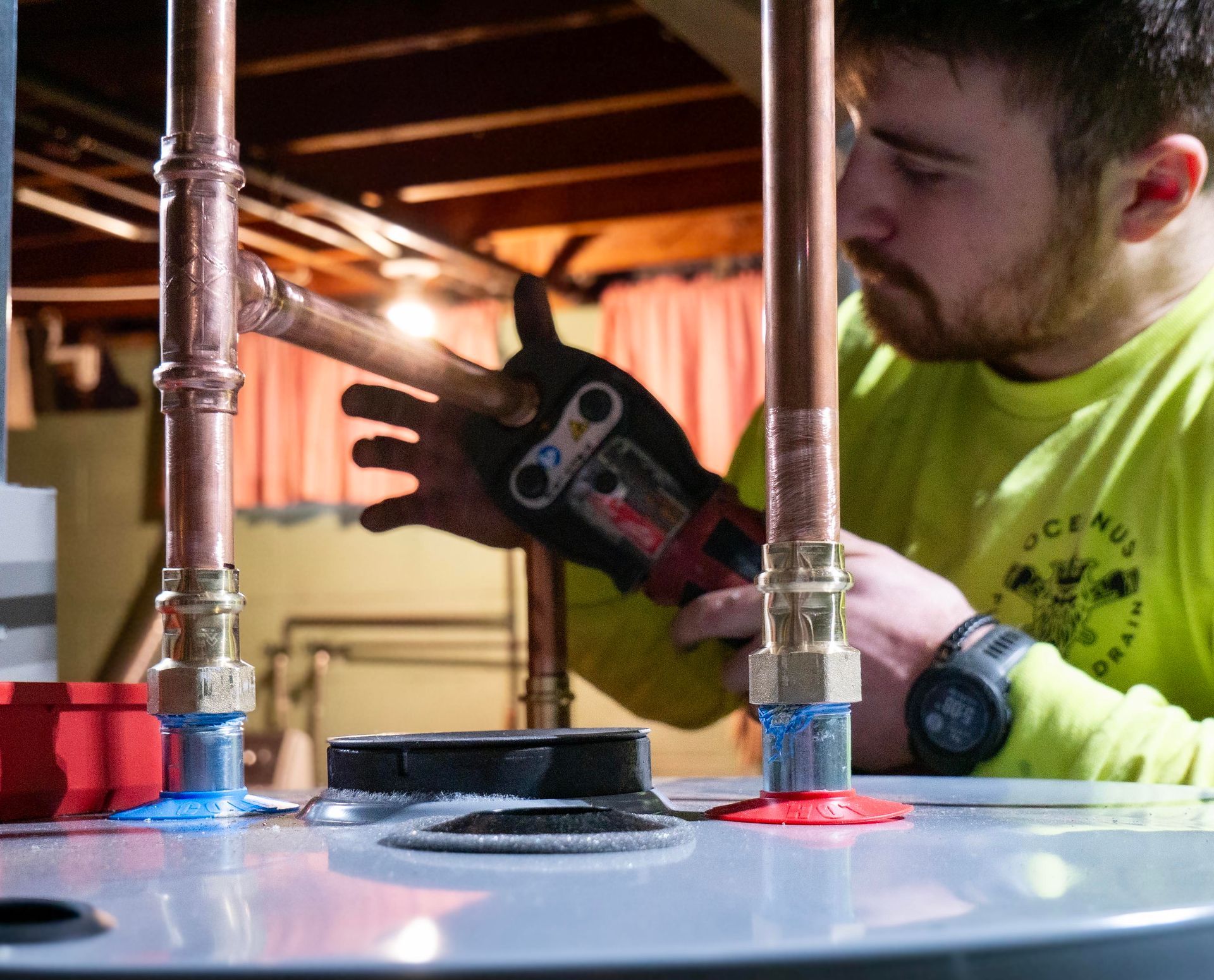 Worker using a power tool to tighten metal pipes on a large tank in a workshop