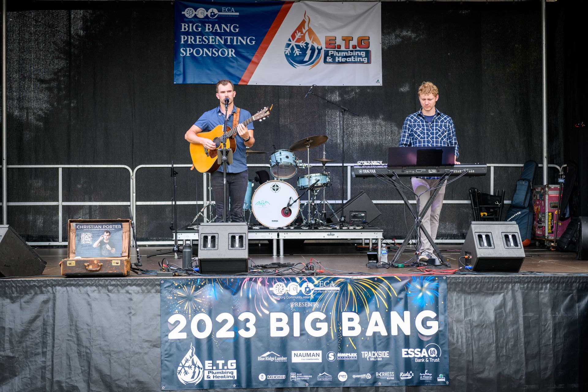 A man is playing a guitar and a man is playing a keyboard on a stage.