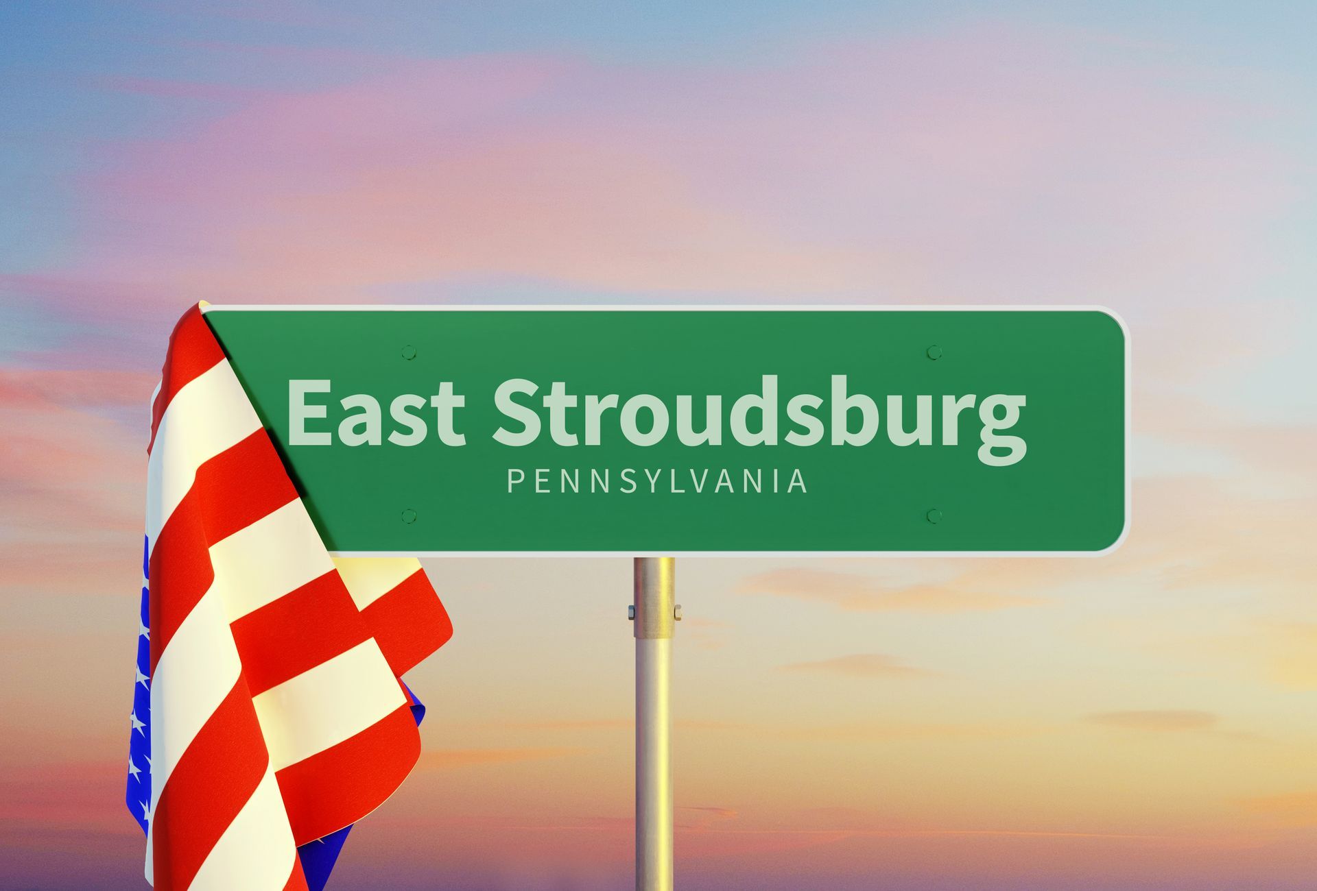East Stroudsburg, Pennsylvania road sign with a waving American flag at sunset