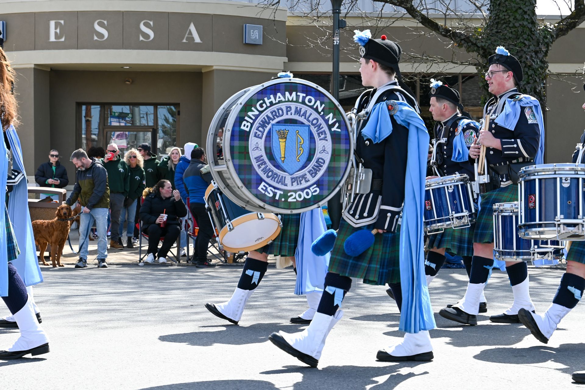 Binghamton Pipe Band marching, blue and black kilts, drum in focus, 