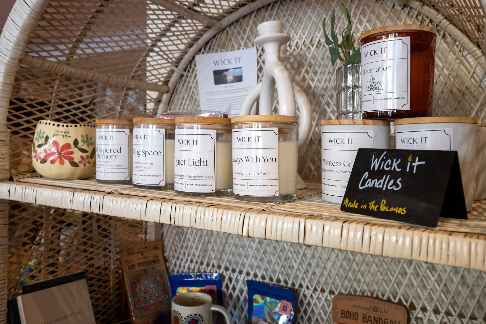 Shelved jars and bottles in wicker baskets at a market stall, with a black sign reading “Wick It Candles.”
