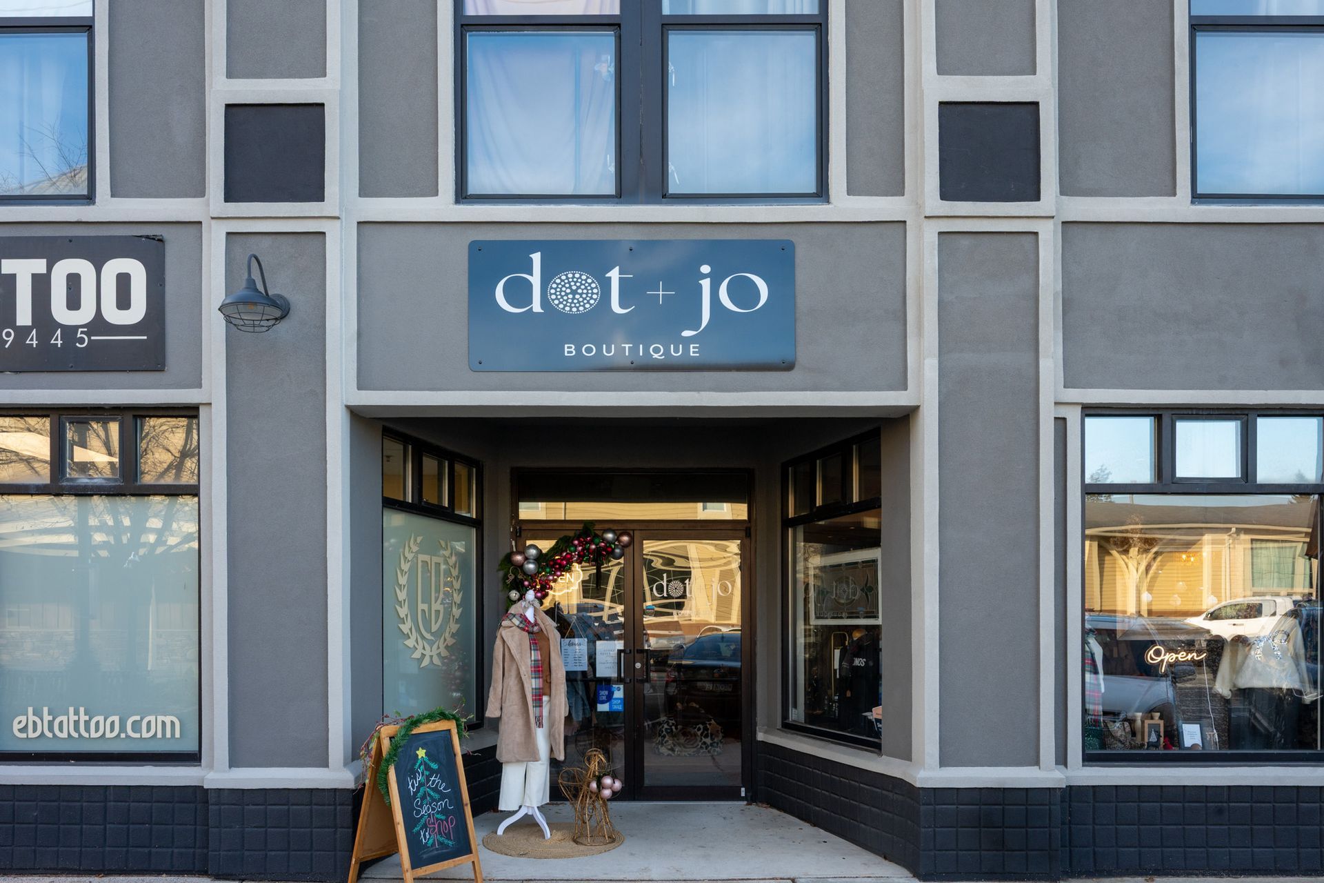 Storefront of a clothing boutique with mannequins and a sidewalk display outside